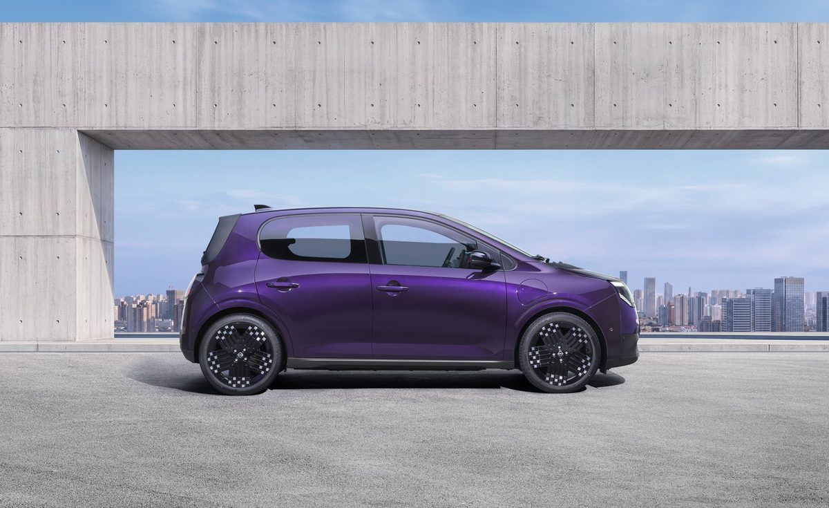 Photograph showcasing a purple Nissan PIXO parked on a rooftop terrace. Side profile highlights aerodynamic shape, black alloy wheels concrete architectural frame, and city skyline backdrop.